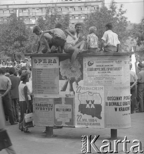 Lipiec 1964, Warszawa, Polska.
Chłopcy siedzą na tablicy ogłoszeniowej i przyglądają się pochodowi na ulicy z okazji Narodowego Święta Odrodzenia Polski, obchodzonego 22 lipca.
Fot. Jerzy Konrad Maciejewski, zbiory Ośrodka KARTA