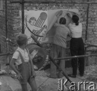 Po 1945, Warszawa, Polska.
Chłopiec patrzy na rysowników, którzy przerysowują na papier malunek na ścianie remontowanego budynku.
Fot. Jerzy Konrad Maciejewski, zbiory Ośrodka KARTA