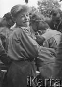 Po 1945, Warszawa, Polska.
Chłopiec pozuje do zdjęcia na tle grupy dzieci i dorosłych, pochylonych nad stołem.
Fot. Jerzy Konrad Maciejewski, zbiory Ośrodka KARTA
