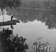 Lata 50. lub 60., Warszawa, Polska.
Mężczyzna stoi na łódce, która cumuje prawdopodobnie przy brzegu Jeziora Wilanowskiego.
Fot. Jerzy Konrad Maciejewski, zbiory Ośrodka KARTA