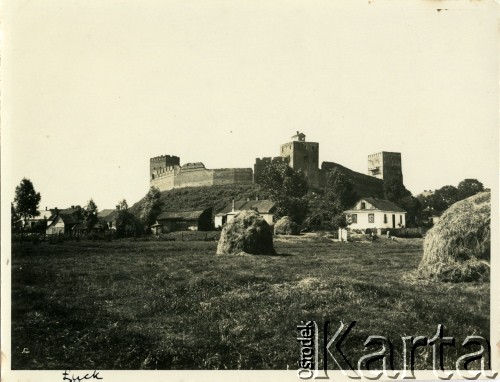 Przed 1939, Łuck, woj. wołyńskie, Polska.
Średniowieczny, murowany zamek księcia Lubarta widziany od strony pól uprawnych. U podnóża góry zamkowej widoczne zabudowania gospodarskie.
Fot. Jerzy Konrad Maciejewski, zbiory Ośrodka KARTA