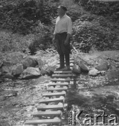 Po 1950, Żaków, woj. warszawskie, Polska.
Mężczyzna stoi na drabinie przerzuconej nad wodą.
Fot. Jerzy Konrad Maciejewski, zbiory Ośrodka KARTA