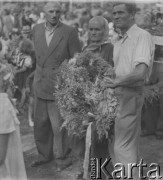 Po 1945, Kanie k. Pruszkowa, woj. warszawskie, Polska.
Mieszkańcy wsi biorą udział w Dożynkach. Kobieta oraz mężczyzna trzymają wieniec.
Fot. Jerzy Konrad Maciejewski, zbiory Ośrodka KARTA
