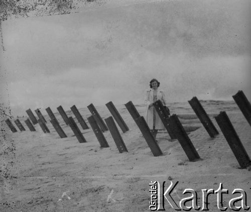 Czerwiec 1946, Dunkierka, Francja.
Kobieta stoi przy zaporach przeciwdesantowych, będących częścią umocnień Wału Atlantyckiego. Wał został zbudowany przez III Rzeszę Niemiecką na okupowanych terenach Zachodniej Europy.
Fot. Jerzy Konrad Maciejewski, zbiory Ośrodka KARTA