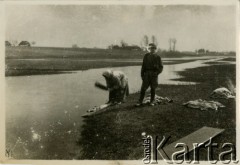 Po 23.02.1919, Bartatów k. Lwowa, Galicja Wschodnia.
Mieszkanka wsi pierze ubrania w rzece. Obok niej stoi żołnierz polski, uczestnik wojny polsko-ukraińskiej. Zdjęcie wykonane po zdobyciu przez żołnierzy I Warszawskiego Batalionu Ochotniczego Oddziału Odsieczy Lwowa WP II RP (od kwietnia 1919 r. 19 pp Odsieczy Lwowa) wsi Bartatów 11.01.1919 r. w ramach operacji przerwania ukraińskiego oblężenia Lwowa.
Fot. Jerzy Konrad Maciejewski, zbiory Ośrodka KARTA