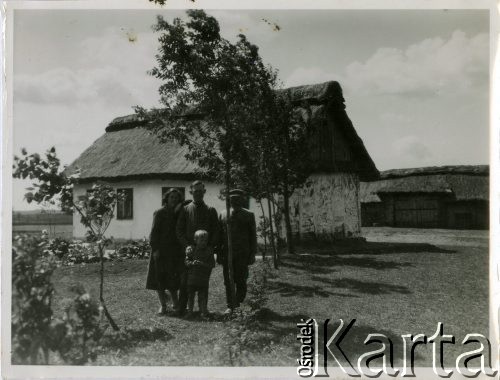 Lata 30., Łosiatyn k. Poczajewa, woj. wołyńskie, Polska.
Osadnik wojskowy z rodziną pozuje do zdjęcia na tle gospodarstwa wiejskiego.
Fot. Jerzy Konrad Maciejewski, zbiory Ośrodka KARTA