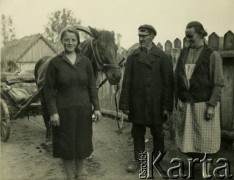 Lata 30., Nur n. Bugiem, woj. białostockie, Polska.
Rodzina chłopska na podwórzu swojego gospodarstwa. Za kobietą stoi koń zaprzęgnięty do wozu.
Fot. Jerzy Konrad Maciejewski, zbiory Ośrodka KARTA