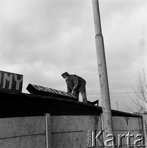 22.12.1970, Szczecin, Polska.
Wydarzenia grudniowe -  teren Stoczni Szczecińskiej im. Adolfa Warskiego, strażnik przemysłowy demontuje hasła strajkowe. 
Fot. Maciej Jasiecki, zbiory Ośrodka KARTA