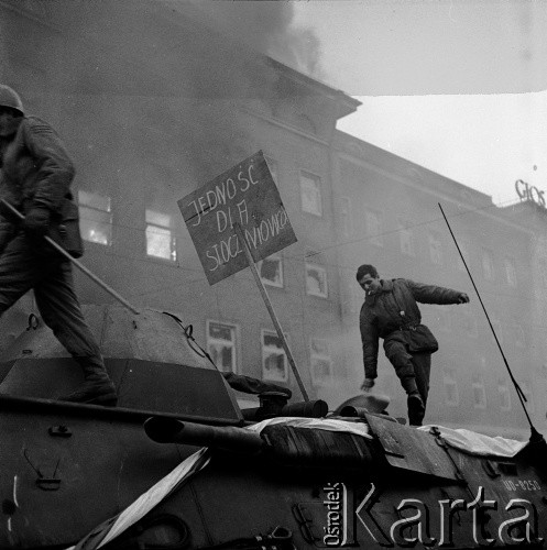 17.12.1970, Szczecin, Polska.
Wydarzenia grudniowe - pl. Żołnierza Polskiego. Żołnierz 12 Dywizji Zmechanizowanej na transporterze opancerzonym „Skot”. W tle płonący gmach KW PZPR i budynek redakcji organu partii - „Głosu Szczecińskiego (z prawej).  
Fot. Maciej Jasiecki, zbiory Ośrodka KARTA