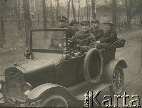 1919-1928, brak miejsca.
Mężczyźni w samochodzie. W 1 rzędzie, po lewej stronie, siedzi funkcjonariusz Policji Państwowej. Z tyłu, 2 z prawej - Jan Piekutowski - urzędnik państwowy.
Fot. NN, kolekcja Jana Piekutowskiego, zbiory Ośrodka KARTA