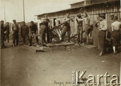 Lipiec - grudzień 1917, Szczypiorno k. Kalisza.
Żołnierze I i II Brygady Legionów, internowani w obozie jenieckim po odmowie złożenia przysięgi na wierność Niemcom. Legioniści obsługujący pompę. W prawym dolnym rogu podpis: 