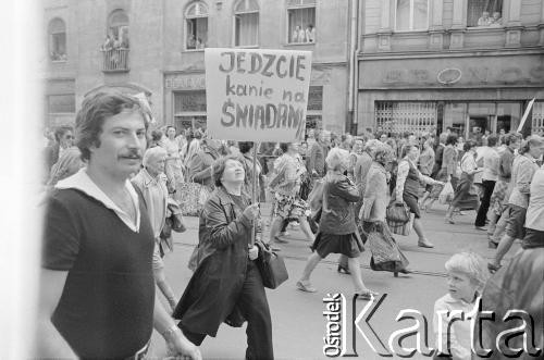 30.07.1981, Łódź, Polska.
Marsz głodowy - jeden z wielu protestów zorganizowanych w kilkunastu miastach Polski na przełomie lipca i sierpnia 1981 roku. Protesty były spowodowane problemami w zaopatrzeniu, zmniejszeniem kartkowych przydziałów mięsa oraz podwyżką cen. Marsz w Łodzi był najliczniejszy. Uczestniczyły w nim głównie kobiety z dziećmi. Na zdjęciu manifestujący na ulicy Piotrkowskiej, kobieta niesie transparent o treści: 