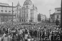 30.07.1981, Łódź, Polska.
Marsz głodowy - jeden z wielu protestów zorganizowanych w kilkunastu miastach Polski na przełomie lipca i sierpnia 1981 roku. Protesty były spowodowane problemami w zaopatrzeniu, zmniejszeniem kartkowych przydziałów mięsa oraz podwyżką cen. Marsz w Łodzi był najliczniejszy. Uczestniczyły w nim głównie kobiety z dziećmi. Na zdjęciu tłum zgromadzony na Placu Wolności podczas marszu. W głębi widać Kościół Zesłania Ducha Świętego.
Fot. Tomasz Tomaszewski, zbiory Ośrodka KARTA