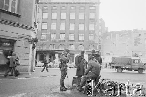 Po 13.12.1981, Warszawa, Polska.
Żołnierze przy koksowniku na ulicy Henryka Rutkowskiego (od listopada 1990 roku ulica Chmielna). W tle budynek przy ulicy Brackiej 25.
Fot. Małgorzata Niezabitowska i Tomasz Tomaszewski, zbiory Ośrodka KARTA 
