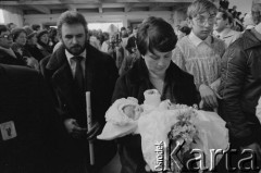 21.03.1982, Gdańsk - Zaspa, Polska.
Chrzest Marii Wiktorii Wałęsy w kościele pw. Opatrzności Bożej. Na pierwszym planie Danuta Wałęsa z dziewczynką na rękach, z lewej ojciec chrzestny Mieczysław Wachowski. 
Fot. Tomasz Tomaszewski, zbiory Ośrodka KARTA
