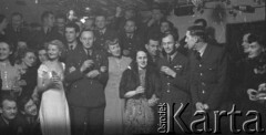 31.12.1943, Ingham, Wielka Brytania. 
Na pierwszym, planie dowódca 300 Dywizjonu mjr pilot Kazimierz Kuzian w otoczeniu pań podczas zabawy sylwestrowej. Na prawo od niego prawd. brytyjski dowódca stacji Hemswell G/Cpt George Francis McPherson z małżonką.
Fot. Zenon Brejwo, zbiory Ośrodka KARTA