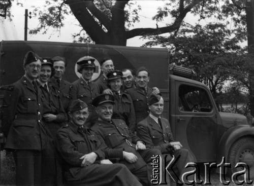 1943, Ingham, Wielka Brytania. 
Siedzą od lewej: mjr pilot Witold Piotrowski (dowódca 309 Dywizjonu Myśliwsko-Rozpoznawczego), prawd. ppłk Antoni Fiumel (Szef Służby Medycznej Polskich Sił Powietrznych) i por. Kornel Wiszniewski (dowódca Sekcji Medycznej 300 Dywizjonu). Za nimi przy ambulansie grupa ochotniczek WAAF (Pomocniczej Lotniczej Służby Kobiet) oraz członków personelu naziemnego Stacji Ingham.
Fot. Zenon Brejwo, zbiory Ośrodka KARTA
