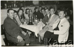 Lata 50., Comodoro Rivadavia, prowincja Chubut, Argentyna.
Przyjęcie z okazji wyścigu samochodowego. Jan Józef Koprowski (trzeci z prawej) - ojciec Enrique Koprowskiego,
Jadwiga Koprowski (trzecia z lewej) - matka Enrique Koprowskiego. Jose Luiz (pierwszy z lewej) - kierowca samochodu, zwycięzca wyścigu.
Fot. NN, zbiory Enrique Koprowskiego, reprodukcje cyfrowe w Bibliotece Polskiej im. Ignacego Domeyki w Buenos Aires (Biblioteca Polaca Ignacio Domeyko) i w Ośrodku KARTA w Warszawie.
