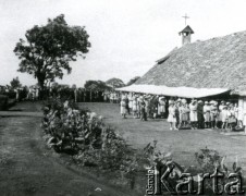 1942-1948, Tenger, Tanganika.
Mieszkańcy osiedla dla polskich uchodźców przed kościołem.  W latach 1942-1948 przebywał tam ofiarodawca zdjęć Leszek Ferency z matką Marią i siostrą Barbarą.
[Polscy uchodźcy w 1942 trafili do Iranu wraz z nowoutworzonym Wojskiem Polskim pod dowództwem generała Władysława Andersa (w dwóch rzutach ewakuacyjnych z ZSRR w marcu i sierpniu). W sumie oprócz wojska dotarło tam 38 tysięcy Polaków, z czego ponad połowę stanowiły dzieci i młodzież. Ok. 20 tys. znalazło się następnie w Afryce, polskie osiedla znajdowały się przede wszystkim w: Ugandzie, Kenii, Tanganice, Rodezji Północnej i Rodezji Południowej, Związku Południowej Afryki. Tengeru było największym polskim osiedlem uchodźczym w Afryce].
Fot. NN, zbiory Ośrodka KARTA, przekazał Leszek Ferency