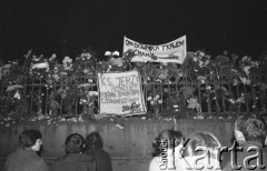 3.11.1984, Warszawa, Polska.
Pogrzeb księdza Jerzego Popiełuszki zamordowanego przez funkcjonariuszy Służby Bezpieczeństwa. Uroczystość odbyła się w kościele Świętego Stanisława Kostki na Żoliborzu, zgromadziła tysiące ludzi. Na zdjęciu ludzie przed ogrodzeniem, na którym zawieszono kwiaty i transparenty z napisem: „Ks. Jerzy przyrzekamy pokonać razem z Tobą czerwonego smoka”, „Orędownika prawdy żegnamy”.
Fot. Maciej Czarnocki, zbiory Ośrodka KARTA.