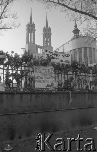 3.11.1984, Warszawa, Polska.
Pogrzeb księdza Jerzego Popiełuszki zamordowanego przez funkcjonariuszy Służby Bezpieczeństwa. Uroczystość odbyła się w kościele Świętego Stanisława Kostki na Żoliborzu, zgromadziła tysiące ludzi. Na zdjęciu kościół i jego ogrodzenie, na którym zawieszono kwiaty i transparenty z napisem: 
