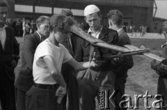 1948, Katowice, Polska.
Ogólnopolskie Zawody Modeli Latających, zawodnicy ze swoim modelem, w tle hangar na lotnisku.
Fot. Kazimierz Seko, zbiory Ośrodka KARTA