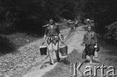 Sierpień 1950, Zakopane, Polska.
Rajd Tatrzański, góral niosący wiadra z wodą na koromyśle, obok niego góralka z dwiema kankami.
Fot. Kazimierz Seko, zbiory Ośrodka KARTA
