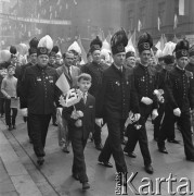 1.05.1969, Katowice, Polska.
Pochód pierwszomajowy na ulicach miasta, górnicy w galowych strojach i chłopiec w garniturze niosący chorągiewkę ozdobioną sztucznymi kwiatkami i cyfrą 