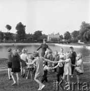 Sierpień 1970, Zagórze lub Kobyłczyce, woj. Katowice, Polska.
Klub Dziecięcy Związku Młodzieży Wiejskiej, grupa dzieci bawiących się na łące razem z wychowawczynią.
Fot. Kazimierz Seko, zbiory Ośrodka KARTA
