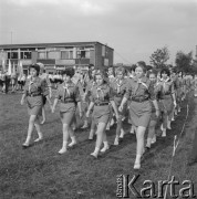 1973, brak miejsca, Polska.
Grupa harcerek maszeruje czwórkami, w tle biało-czerwone flagi i budynek.
Fot. Kazimierz Seko, zbiory Ośrodka KARTA