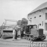 lata 60-te, brak miejsca, Polska.
Pracownicy Państwowego Gospodarstwa Rolnego, na podwórzu przed magazynem stoją maszyny rolnicze.
Fot. Kazimierz Seko, zbiory Ośrodka KARTA.