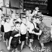 Czerwiec 1969, Warszawa, Polska.
Szkoła podstawowa, zakończenie roku szkolnego, uczniowie wręczają goździki nauczycielce, z lewej portret Władysława Gomułki.
Fot. Jarosław Tarań, zbiory Ośrodka KARTA [69-133]
 
