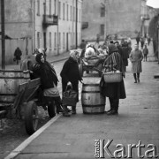 Październik 1970, Opoczno, Polska
 Dzień targowy, kobiety w strojach regionalnych obok beczki stojącej na chodniku.
 Fot. Jarosław Tarań, zbiory Ośrodka KARTA [70-225]
   
