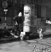 31.03.1970, Warszawa, Polska.
 Kobieta rozklejająca plakaty na słupie ogłoszeniowym.
 Fot. Jarosław Tarań, zbiory Ośrodka KARTA [70-322]
   
