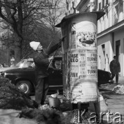 31.03.1970, Warszawa, Polska.
 Kobieta rozklejająca plakaty na słupie ogłoszeniowym.
 Fot. Jarosław Tarań, zbiory Ośrodka KARTA [70-322]
   
