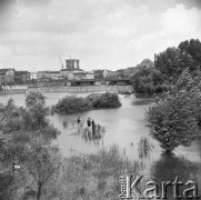 Lipiec 1970, Warszawa, Polska.
 Dzieciaki łowiące ryby w rzece rozlanej na skutek długotrwałych opadów deszczu, w tle fragment miasta.
 Fot. Jarosław Tarań, zbiory Ośrodka KARTA [70-274]
   

