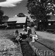25-30.05.1971, Niedzica, Polska
 Kobieta piorąca w strumyku, obok przyglądające się dzieci.
 Fot. Jarosław Tarań, zbiory Ośrodka KARTA [71-28]
   
