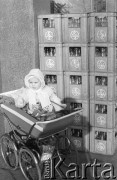6.04.1975, Warszawa, Polska.
Dziecko w wózku, w tle skrzynki z pustymi butelkami na mleko.
Fot. Jarosław Tarań, zbiory Ośrodka KARTA [75-231]
 
