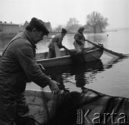 20-21.11.1979, Ostróda, woj. olsztyńskie, Polska.
Rybacy Zespołu Ostróda - połów ryb. W oddali widoczny jest zarys drzew i domów na drugim brzegu jeziora.
Fot. Jarosław Tarań, zbiory Ośrodka KARTA [79-19] 
