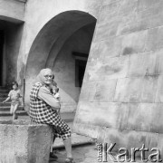 23.08.1979, Tarnów, Polska.
Starsza kobieta siedząca przed podcieniem kamienicy. Na drugim planie widoczne są dzieci.
Fot. Jarosław Tarań, zbiory Ośrodka KARTA [79-9] 

