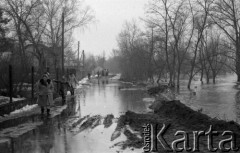 Marzec 1979, Rybienko, woj. Ostrołęka, Polska.
Powódź - mieszkanki miejscowości przeprawiają się przez podtopioną drogę. W oddali widoczna jest zabudowa mieszkalna oraz drzewa.
Fot. Jarosław Tarań, zbiory Ośrodka KARTA [79-29] 
