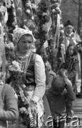 12.04.1981, Łyse, woj. Ostrołęka, Polska
Niedziela Palmowa na Kurpiach, kobieta w kurpiowskim stroju z palmą, w tle ksiądz.
Fot. Jarosław Tarań, zbiory Ośrodka KARTA [81-11] 
