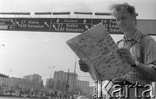 2.09.1985, Warszawa, Polska.
Mężczyzna z mapą Polski stojący na ulicy, w tle drogowskaz i bloki.
Fot. Jarosław Tarań, zbiory Ośrodka KARTA [85-26]