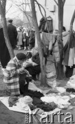22.11.1986, Warszawa - Rembertów, Polska.
Bazar z ubraniami w Rembertowie, handlarka w kraciastym palcie obok swojego towaru, część ubrań wisi na sznurkach między drzewami.
Fot. Jarosław Tarań, zbiory Ośrodka KARTA, [86-43] 
