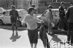 1986, Warszawa, Polska.
Lany poniedziałek, kobieta w mokrym ubraniu oblana wodą na ulicy, z tyłu kilku roześmianych chłopców z wiadrami.
Fot. Jarosław Tarań, zbiory Ośrodka KARTA [86-192] 
