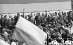 1.05.1986, Warszawa, Polska.
Pochód pierwszomajowy, manifestanci z biało-czerwoną flagą przechodzą przed trybuną honorową, na trybunie w środku (w ciemnym garniturze) stoi Wojciech Jaruzelski.
Fot. Jarosław Tarań, zbiory Ośrodka KARTA [86-61] 
