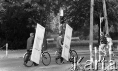 1988-1989, Żyrardów, woj. Skierniewice, Polska
Dwaj mężczyźni przewożący drzwi na rowerach.
Fot. Jarosław Tarań, zbiory Ośrodka KARTA [89-73] 
