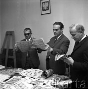 21.08.1968, Warszawa, Polska.
Fałszywe dolary przechwycone przez Komendę Miejską Milicji Obywatelskiej - mężczyźni oglądają podrobione banknoty, godło państwowe na ścianie.
Fot. Jarosław Tarań, zbiory Ośrodka KARTA

