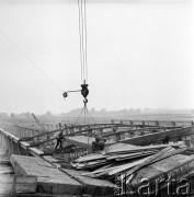 23.08.1968, Bzie Zameckie k./Jastrzębia-Zdroju, woj. katowickie, Polska
Budowa Fabryki Domów - zakładu produkującego płyty oraz elementy przestrzenne wykorzystywane przy budowie nowoczesnych bloków mieszkalnych. Robotnicy montują transportowany przez dźwig element dachu. 
Fot. Jarosław Tarań, zbiory Ośrodka KARTA