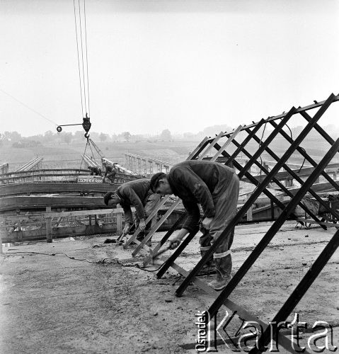 23.08.1968, Bzie Zameckie k./Jastrzębia-Zdroju, woj. katowickie, Polska
Budowa Fabryki Domów - zakładu produkującego płyty oraz elementy przestrzenne wykorzystywane przy budowie nowoczesnych bloków mieszkalnych. Robotnicy pracują nad stalowymi konstrukcjami na dachu, na dalszym planie - montaż dachu.
Fot. Jarosław Tarań, zbiory Ośrodka KARTA